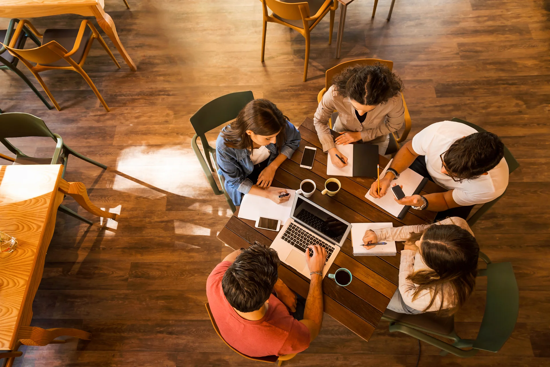 Arbetskollegor sitter runt ett bord och antecknar